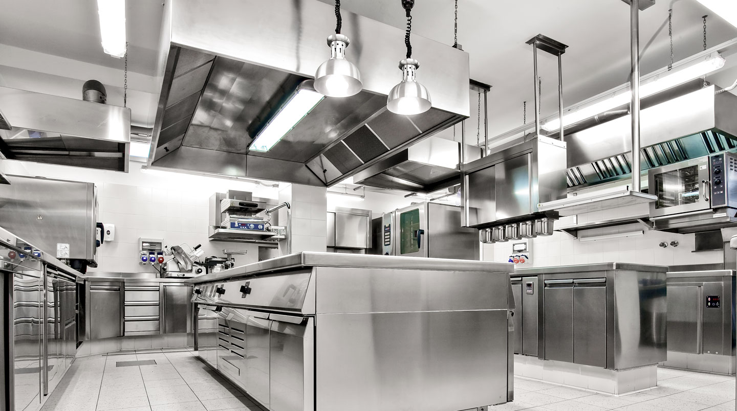 Chef cuisinant sur un piano à gaz professionnel avec flammes visibles dans une cuisine de restaurant moderne