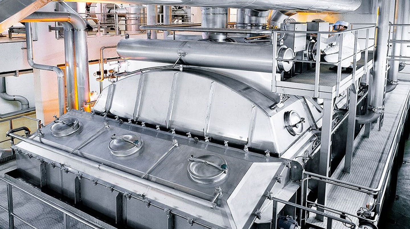 Technicien surveillant un équipement de cuisson industriel au gaz dans une usine agroalimentaire française